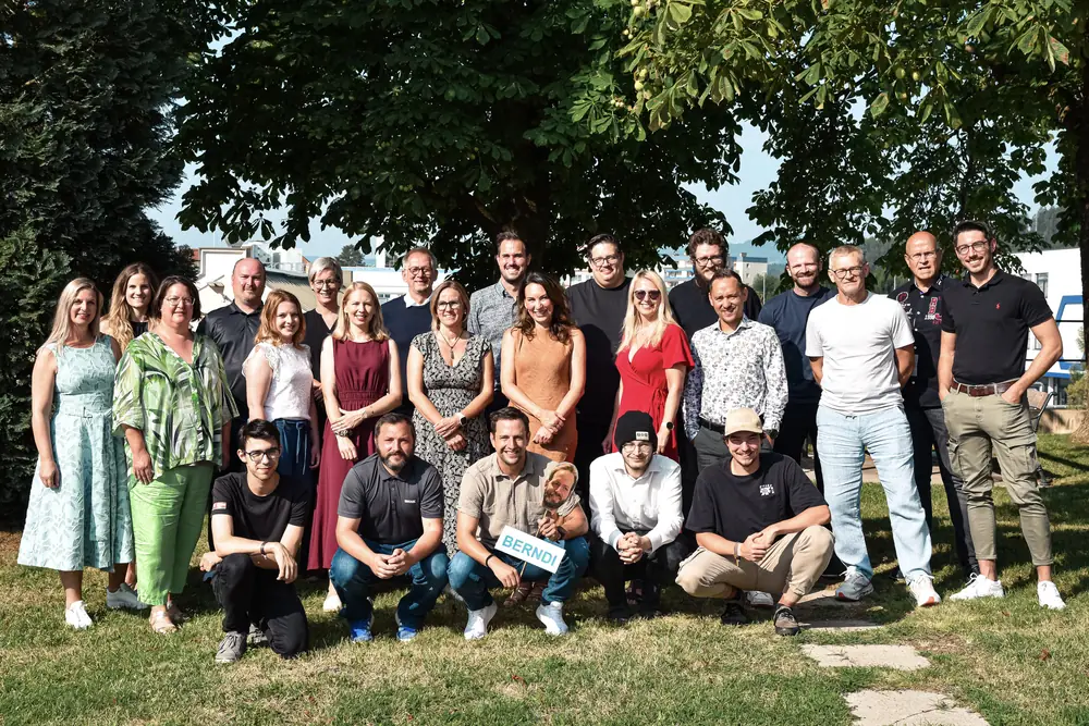 Das gesamte Team versammelt zum Gruppenfoto im Freien unter einem Kastanienbaum