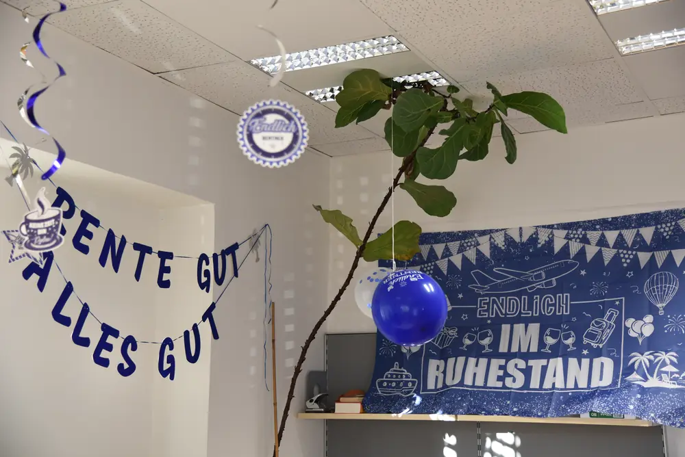Das geschmückte Büro mit „Rente gut, alles gut“-Girlande und „Endlich im Ruhestand“-Banner