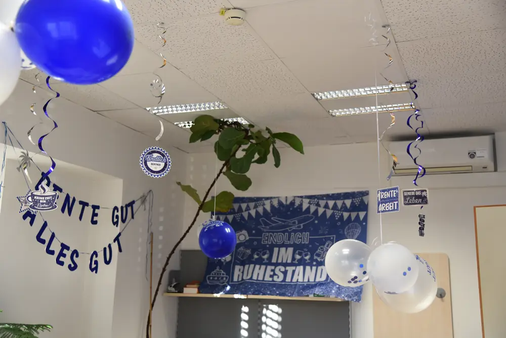 Blick zur Decke: blaue und weiße Ballons, Girlanden und Deko-Schilder