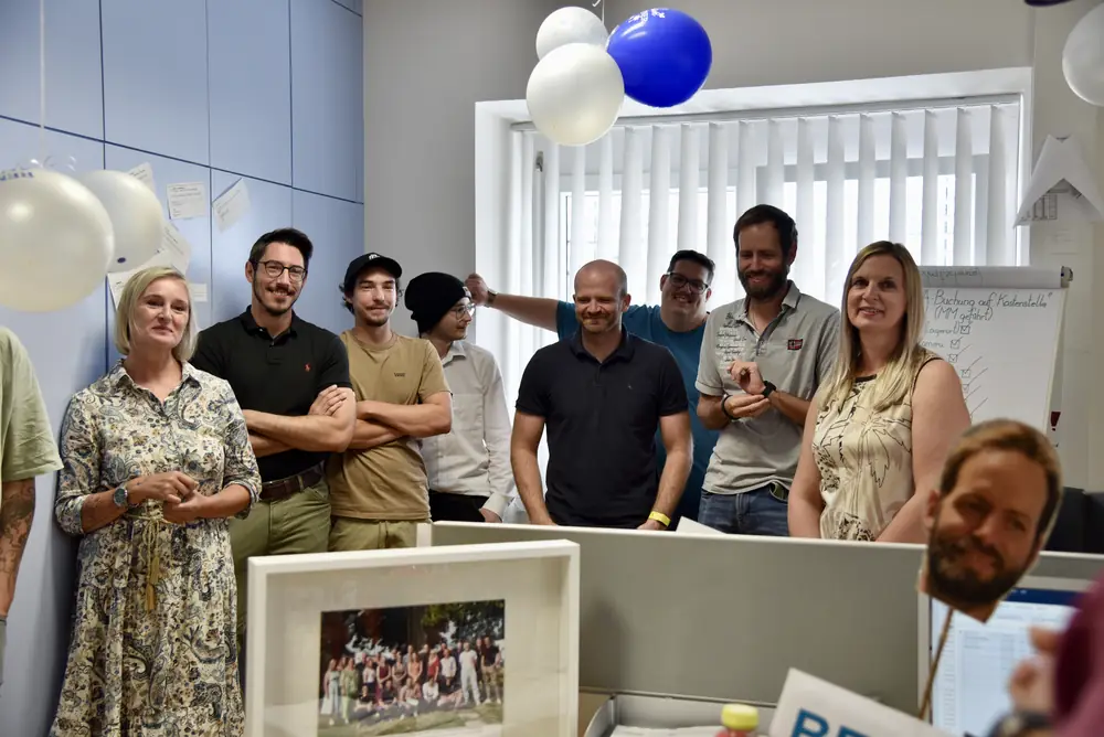 Ein Teil des Teams steht lachend im Büro zusammen