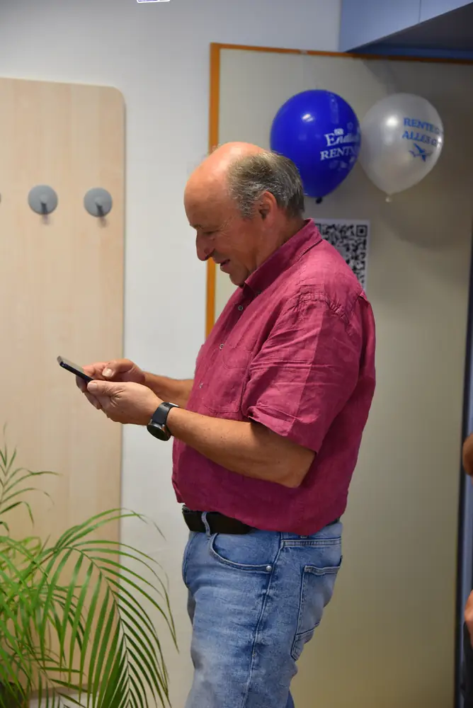 Günter liest etwas auf seinem Handy, Ballons im Hintergrund