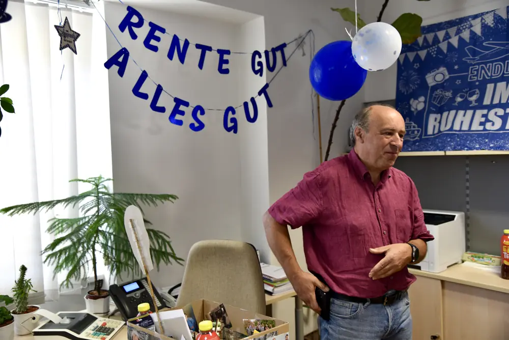 Günter im geschmückten Büro unter der „Rente gut, alles gut“-Girlande