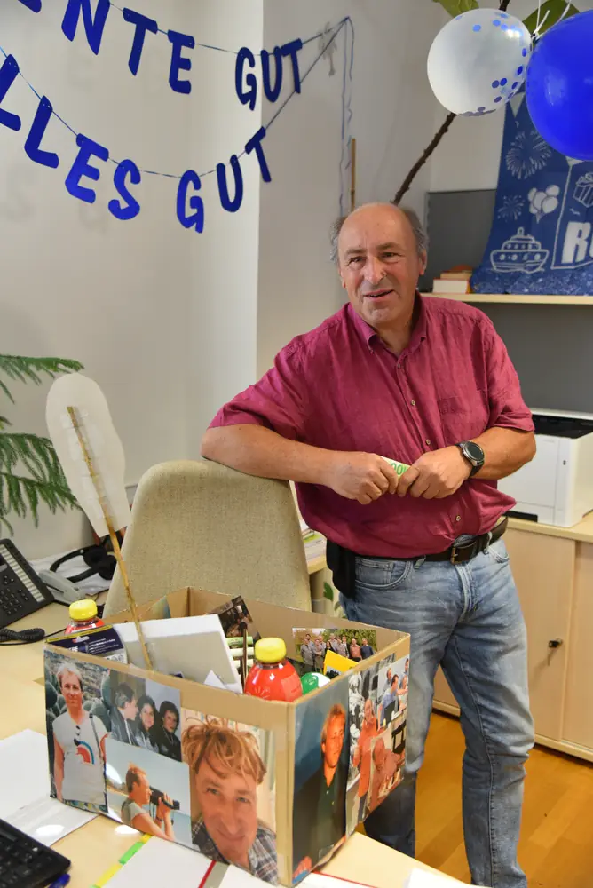 Günter an seinem Schreibtisch hinter der Geschenkkiste mit der Fotocollage