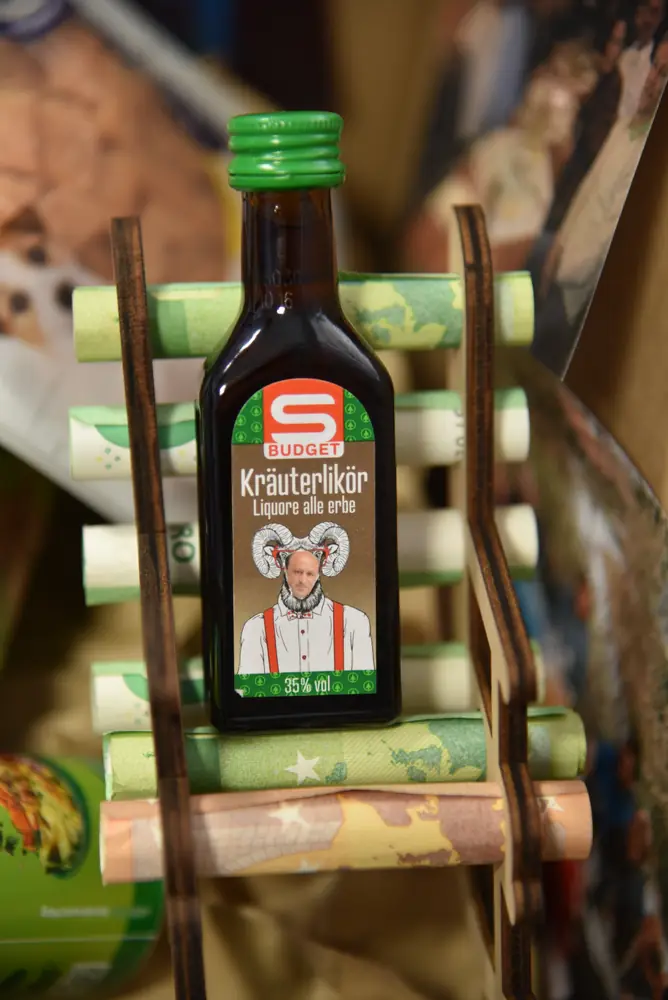 Detail: ein Mini-Kräuterlikör mit eigens gestaltetem Etikett auf der Geschenkleiter
