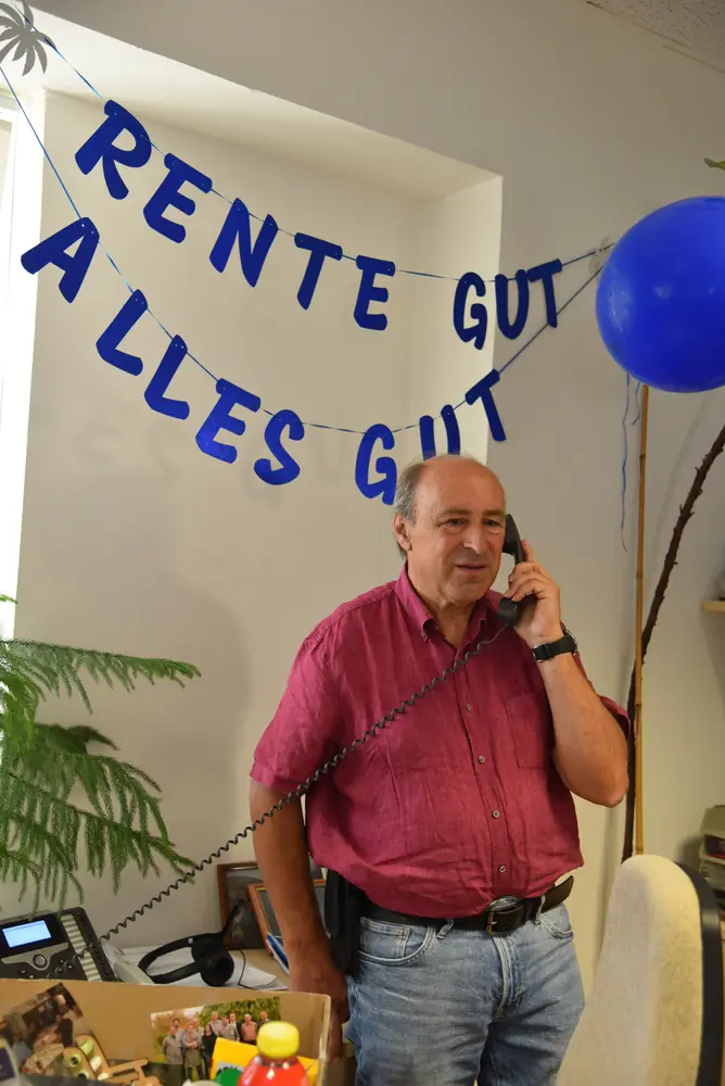 Günter telefoniert lächelnd im geschmückten Büro